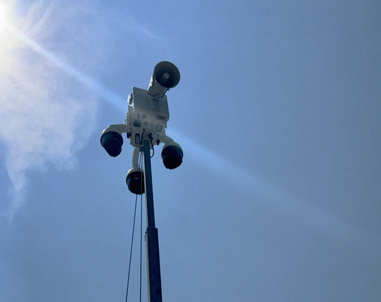 A photo of a mobile speaker/surveillance system against a blue sky